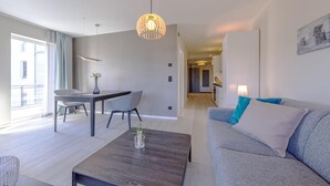 Una sala de estar moderna con un sofá gris, una mesa de centro y una zona comedor con una mesa y sillas.