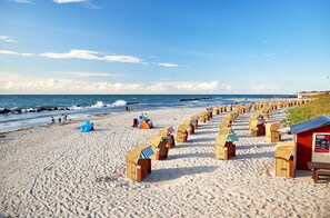 Uma praia com fileiras de cabanas de praia e uma torre de salva-vidas.