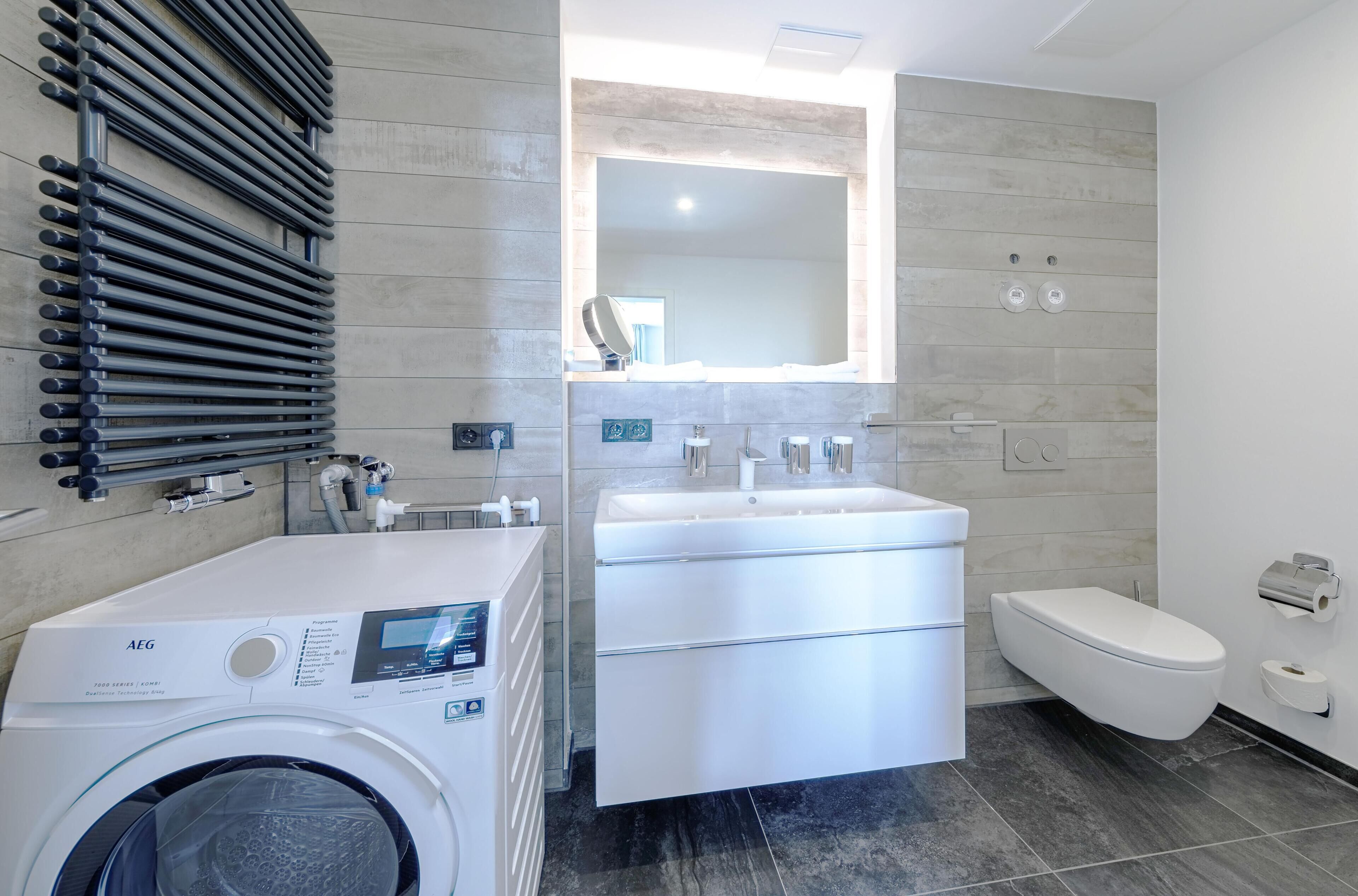 Un bagno moderno con lavatrice, lavandino e water.