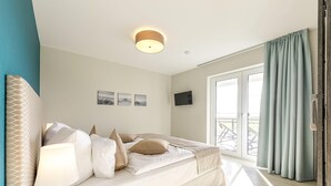 A bedroom with a bed, a bedside lamp, a TV, and a window with curtains. - 5 star vacation apartment "Strandlounge" in Wustrow on the Baltic Sea (Wustrow)