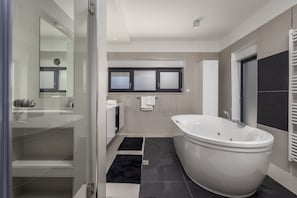 Ein modernes Badezimmer mit einer freistehenden Badewanne, einer Duschkabine und einem Waschtisch mit Spiegel.