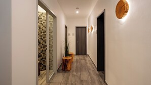 Un pasillo con piso de patrón de cuadros, mesas redondas de madera y un adorno de pared de madera.