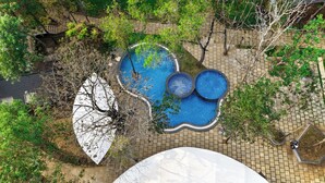 An aerial view of a landscaped area with a circular pool, paved walkways, and surrounding greenery. - TGI Redolent Resort & Spa (Somvarpet)