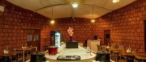 Un restaurante con paredes de ladrillo, una barra central con productos alimenticios y mesas con sillas.