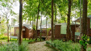 A pathway leading to traditional-style buildings surrounded by lush greenery. - TGI Redolent Resort & Spa (Somvarpet)
