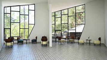 A spacious room with large windows, tiled floor, and multiple seating areas.