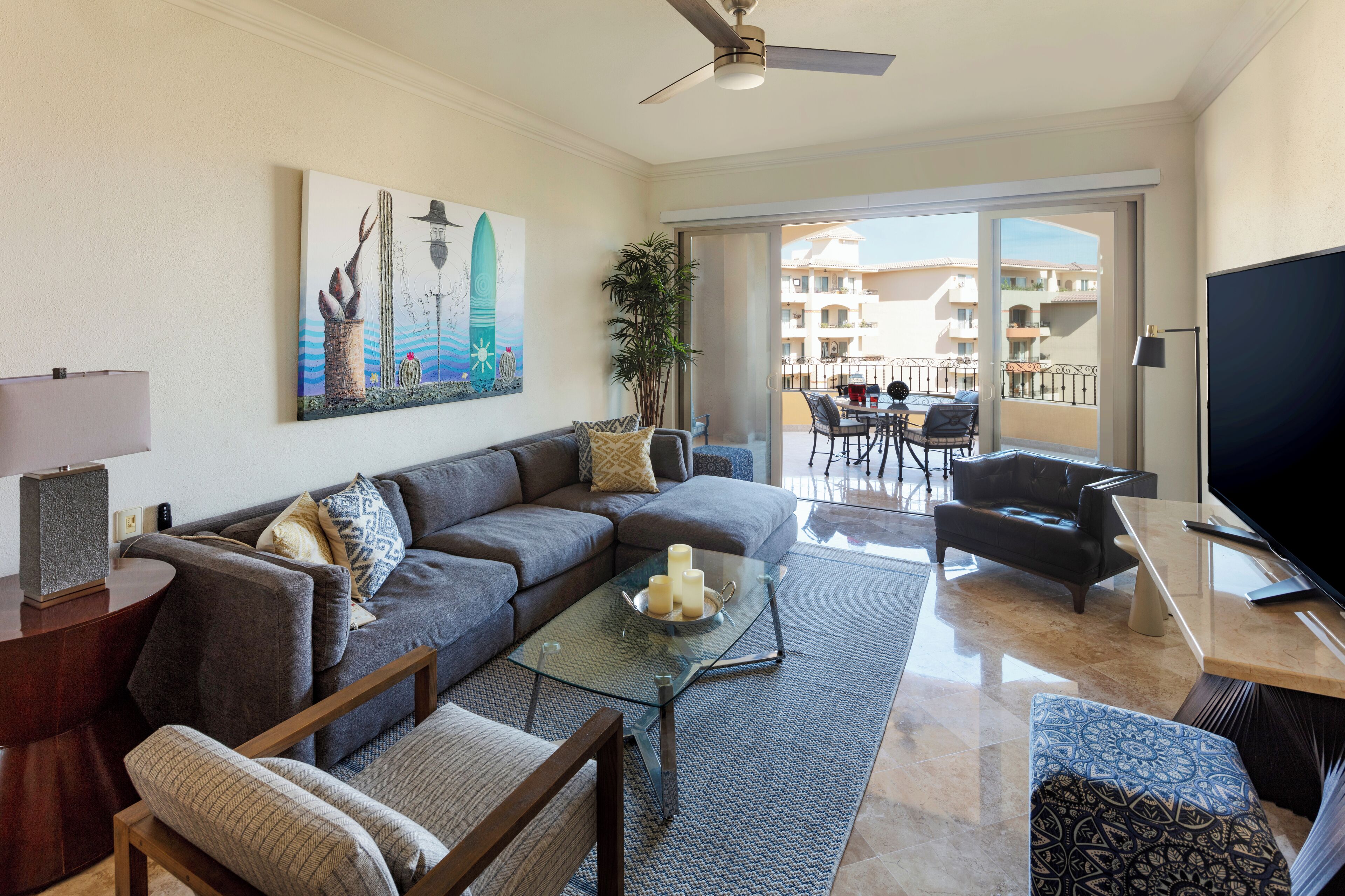 A modern living room with a sofa, coffee table, TV, and balcony view.