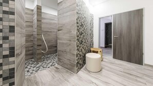 A modern bathroom with a shower, tiled walls, and a wooden floor. - Unforgettable vacation in the Kapitänslounge vacation apartment (Wustrow)