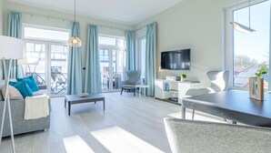 A modern living room with a sofa, armchair, dining table, and a TV. - Unforgettable vacation in the Kapitänslounge vacation apartment (Wustrow)