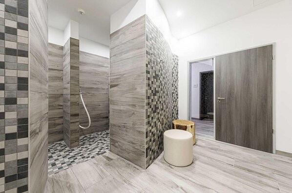 Un baño moderno con ducha, paredes de azulejos y suelo de madera.