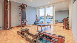 Un gimnasio con equipo de ejercicio, ventanas amplias y vistas a la ciudad.