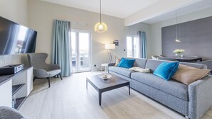 Un salon moderne avec un canapé gris, une table basse, un téléviseur et un coin repas comprenant une table et des chaises.