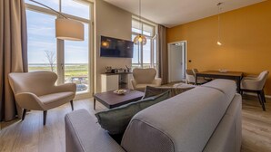 Un salon moderne avec un canapé, des fauteuils, une table basse et un téléviseur.