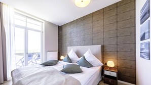 Une chambre à coucher moderne avec un grand lit, une table de chevet et une vue sur un balcon.