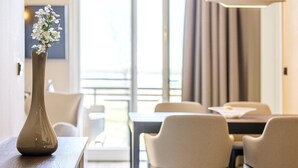 Une chambre d’hôtel dotée d’un coin repas comprenant une table et des chaises, un vase avec des fleurs posé sur la table, et une vue par la fenêtre.