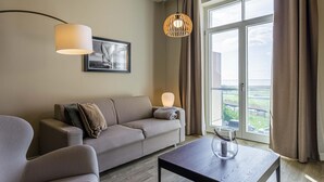 Un salon moderne avec un canapé, une table et une grande fenêtre donnant sur l’extérieur.