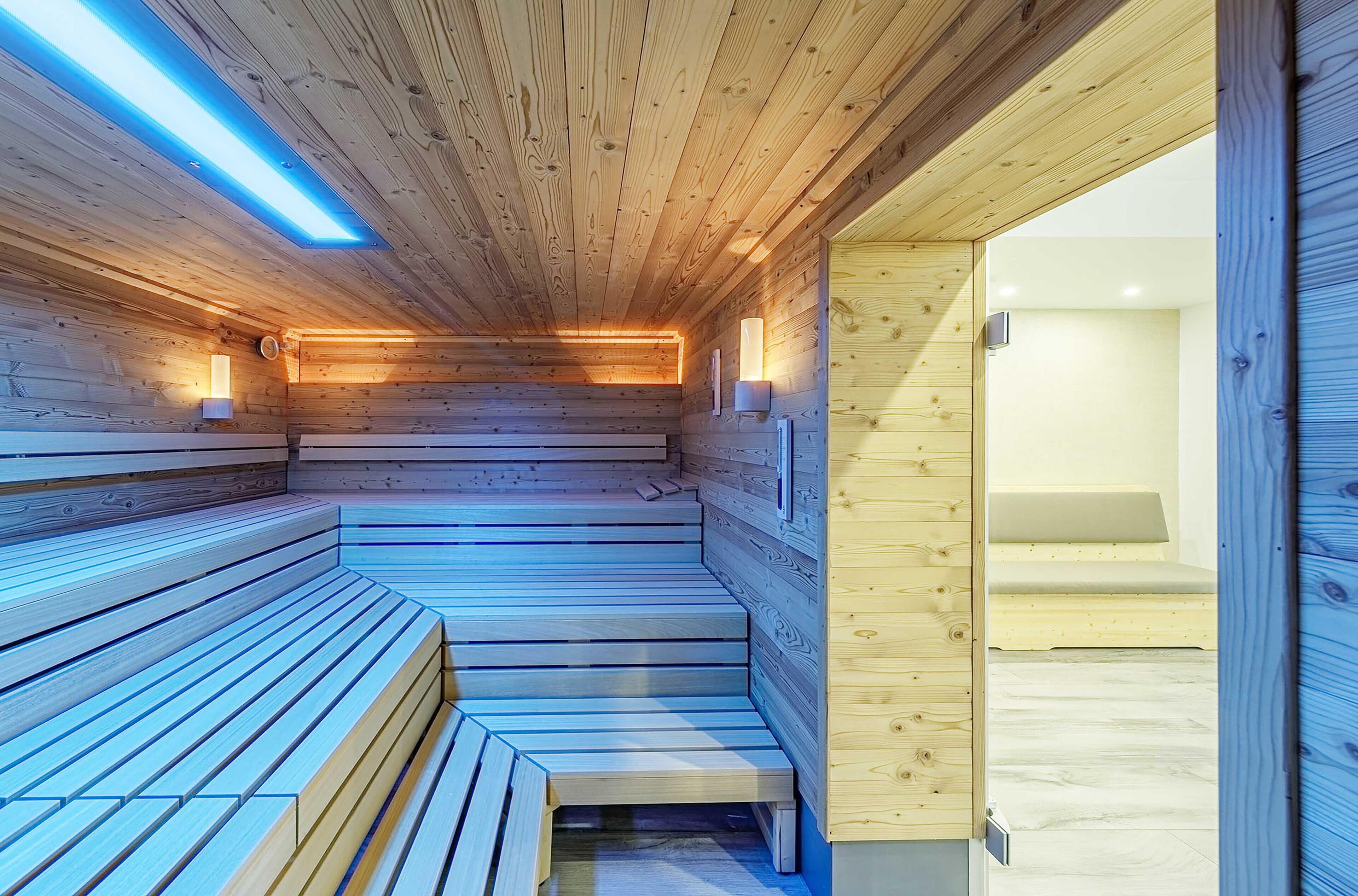 Eine Holzsauna mit Bänken und einer Glastür zu einem Raum.