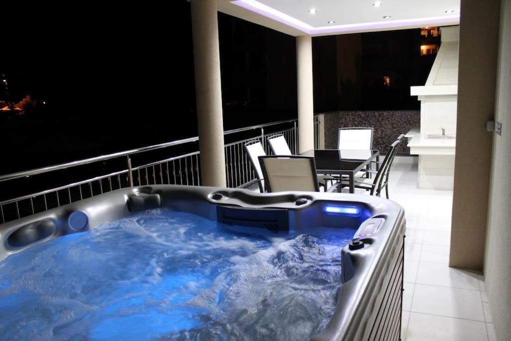 Un jacuzzi en un balcón con una mesa y sillas cerca.