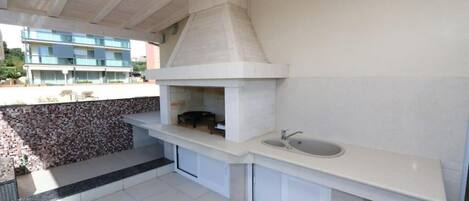 Une cuisine moderne dotée d’un four encastré, d’un évier et d’un pare-feu en pierre.