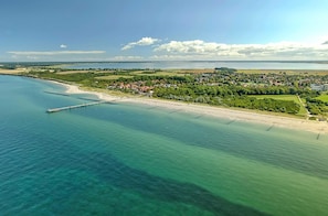 An aerial view of a coastal town with a pier extending into the sea, surrounded by greenery and residential areas. - Wellness Getaway at the Seeräuber Vacation Apartment—Perfect for 6–8 People (Wustrow)