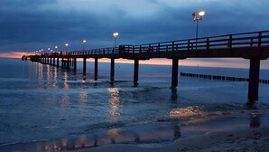 A pier extending into calm waters at dusk with street lamps along its length. - "Vitus Bering Suite" Vacation Rental with a Balcony on the Baltic Sea (Wustrow)