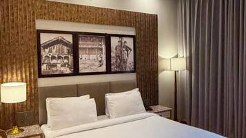 A modern hotel room with a large bed, wooden paneling on the walls, and framed black-and-white photographs.