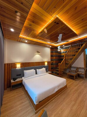 Ein Schlafzimmer mit Holzwandverkleidung, einem Bett, Nachttischen, einer Wandleuchte und einer Treppe.