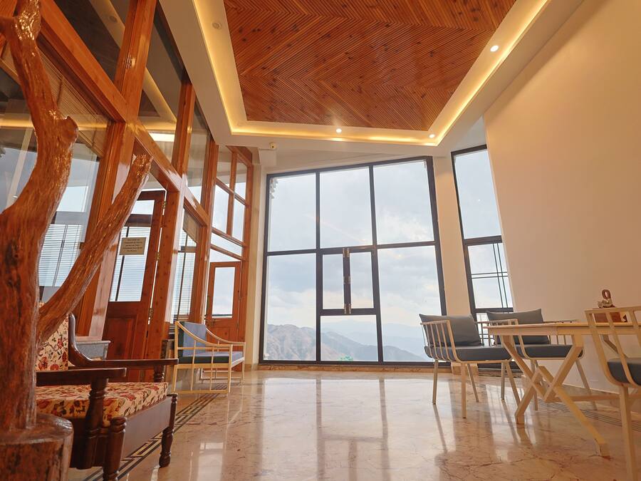 A spacious room with large windows, wooden furniture, and a polished floor.