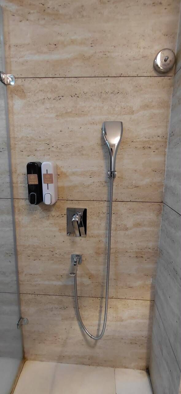 A shower with a handheld showerhead and a wall-mounted control panel.