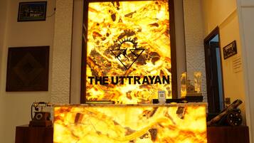 A reception desk with a large illuminated sign reading 'THE UTTRAYAN'.