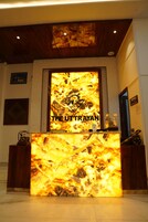 A reception desk with a large illuminated sign reading 'THE UTTRAYAN'.