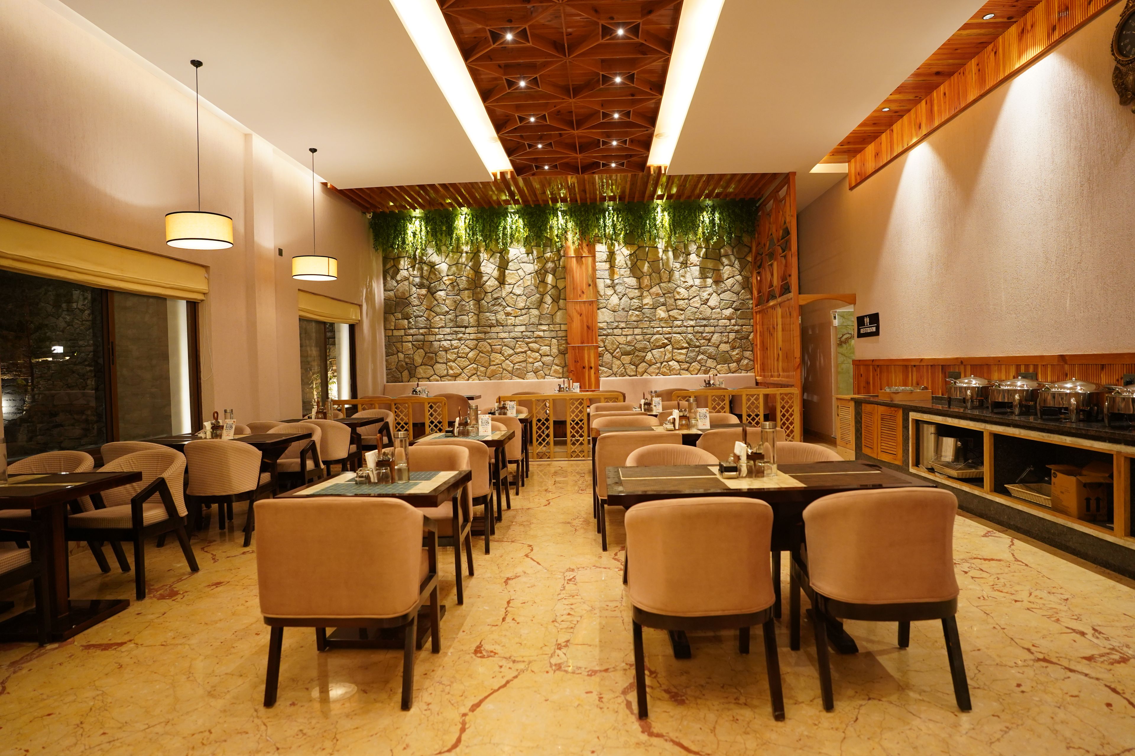 A restaurant with a stone wall, wooden ceiling, and multiple tables and chairs.