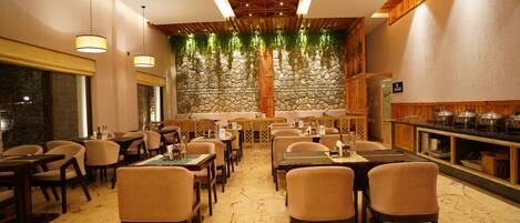 A restaurant with a stone wall, wooden ceiling, and multiple tables and chairs.