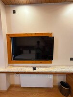 A kitchen with a built-in TV, wooden countertop, and a white appliance below.