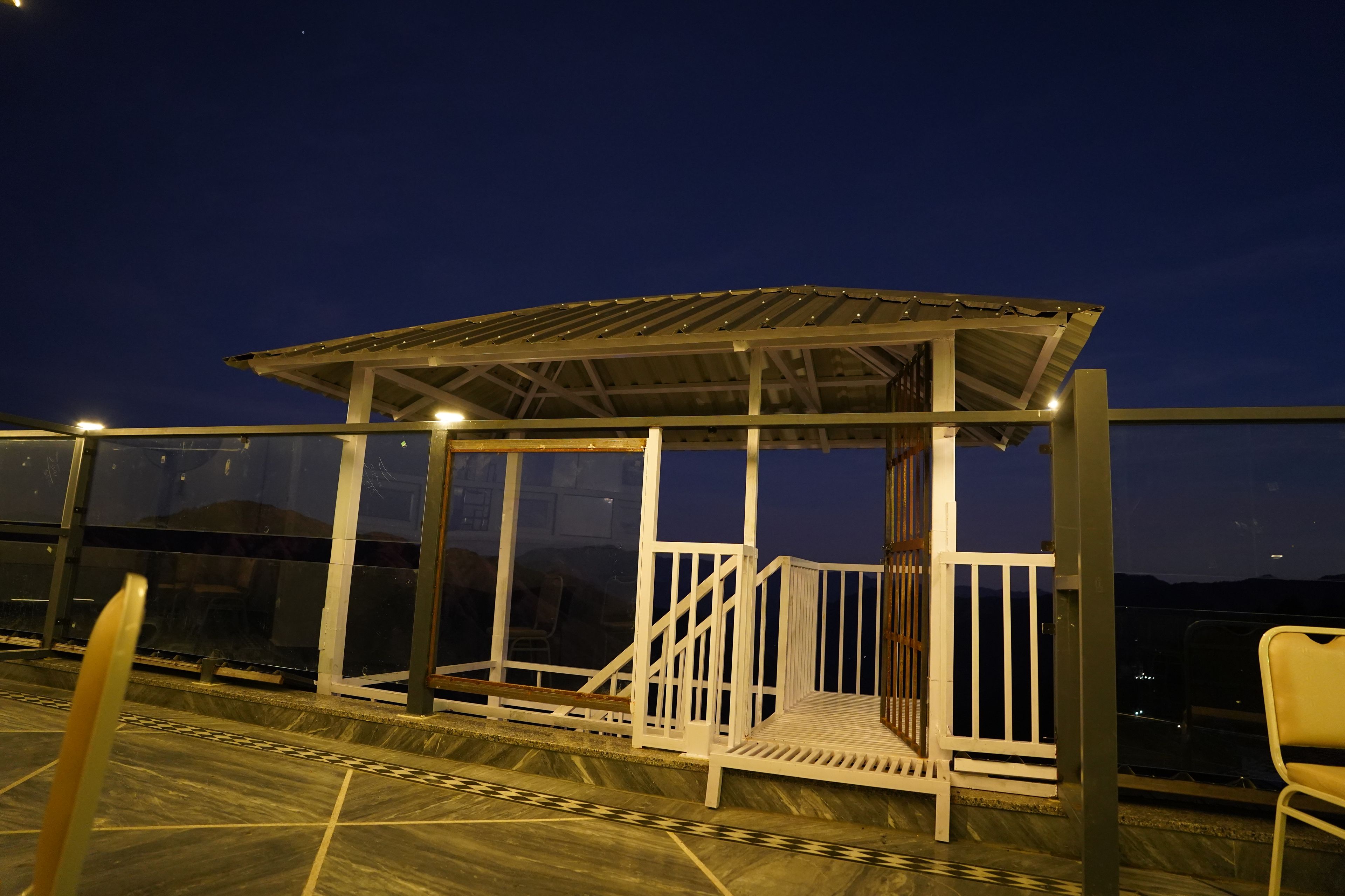 A covered outdoor seating area with a metal roof and white railings.