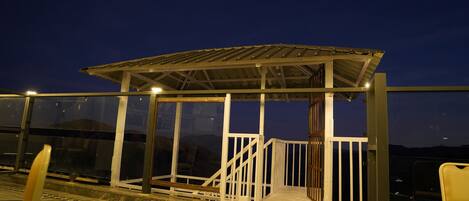 A covered outdoor seating area with a metal roof and white railings.