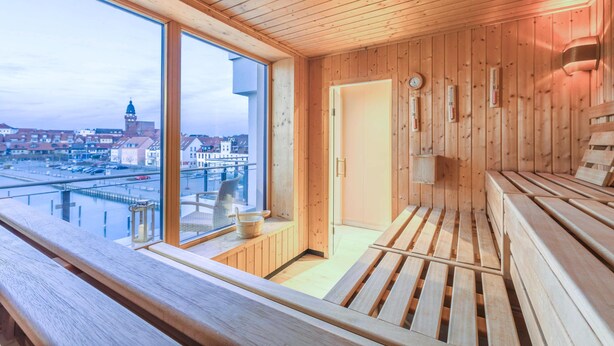 A wooden sauna room with a large window overlooking a cityscape.