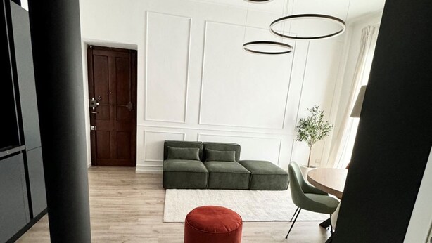 A modern living room with a sectional sofa, a red ottoman, a round table, and a potted plant. - GuestHost - 65 sqm apartment for 4 people, located on the second floor of a building without an elevator, featuring a balcony. Situated in the Lingotto neighborhood, a convenient and well-served area, close to the Regina Margherita Hospital and just minu (Torino)