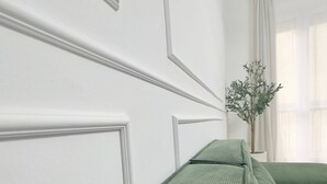A room with white walls, a green sofa, and a potted plant. - GuestHost - 65 sqm apartment for 4 people, located on the second floor of a building without an elevator, featuring a balcony. Situated in the Lingotto neighborhood, a convenient and well-served area, close to the Regina Margherita Hospital and just minu (Torino)