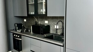A modern kitchen with a built-in microwave, stove, and sink. - GuestHost - 65 sqm apartment for 4 people, located on the second floor of a building without an elevator, featuring a balcony. Situated in the Lingotto neighborhood, a convenient and well-served area, close to the Regina Margherita Hospital and just minu (Torino)