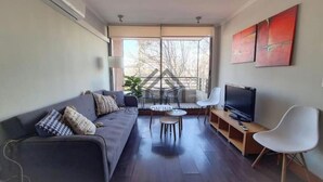 Ett modernt vardagsrum med en soffa, en tv, ett litet bord och en stol.
