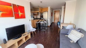 Ett modernt vardagsrum med en platt-TV, en soffa och en matplats med ett bord och stolar.