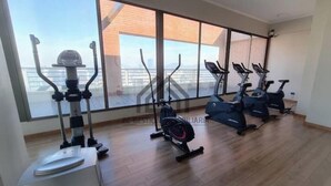 Ett gym med olika träningsmaskiner, stora fönster och ett trägolv.