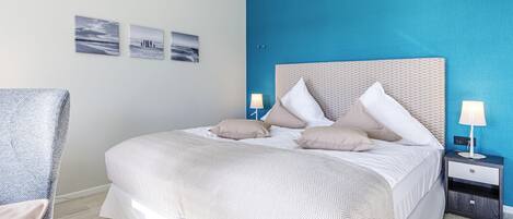 A neatly made bed with a patterned bedspread, two bedside lamps, and a nightstand.