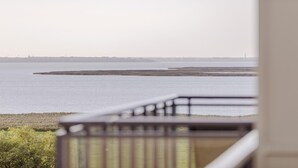 A view from a balcony overlooking a calm body of water with a distant shoreline.