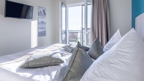 Une chambre d’hôtel avec un lit, un téléviseur fixé au mur et une fenêtre avec des rideaux.