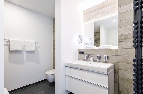 Une salle de bain moderne avec un lavabo blanc, un miroir et un porte-serviettes.