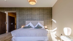 A modern bedroom with a large bed, a wooden wardrobe, and a white chair.