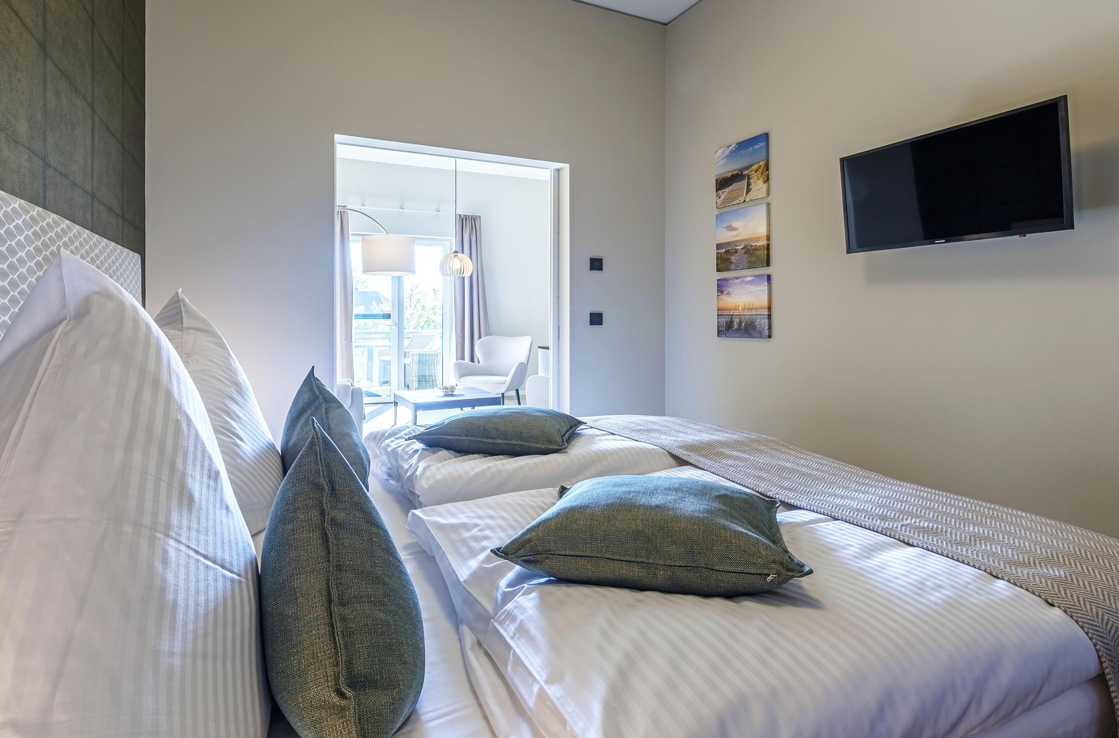 A hotel room with two beds, a flat-screen TV, and a large window.