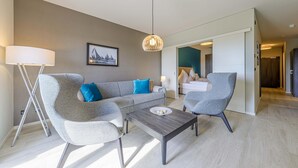 Una sala de estar moderna con un sofá gris, dos sillones, una mesa de centro y una lámpara colgante.